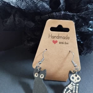 boucles d'oreilles chats squelettes d'un côté et chat noir de l'autre