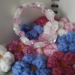 bracelet à roses blanche et perles roses transparente poser sur un tapis de fleur en crochet